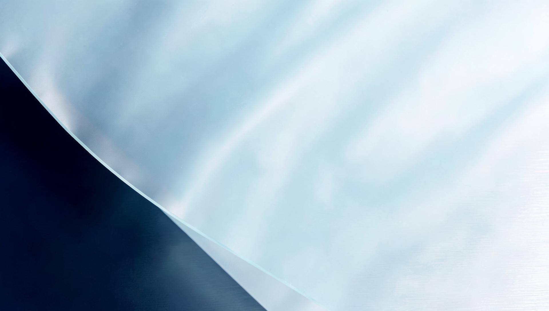 Abstract detail of translucent packaging film and brushed steel in soft blue and white light
